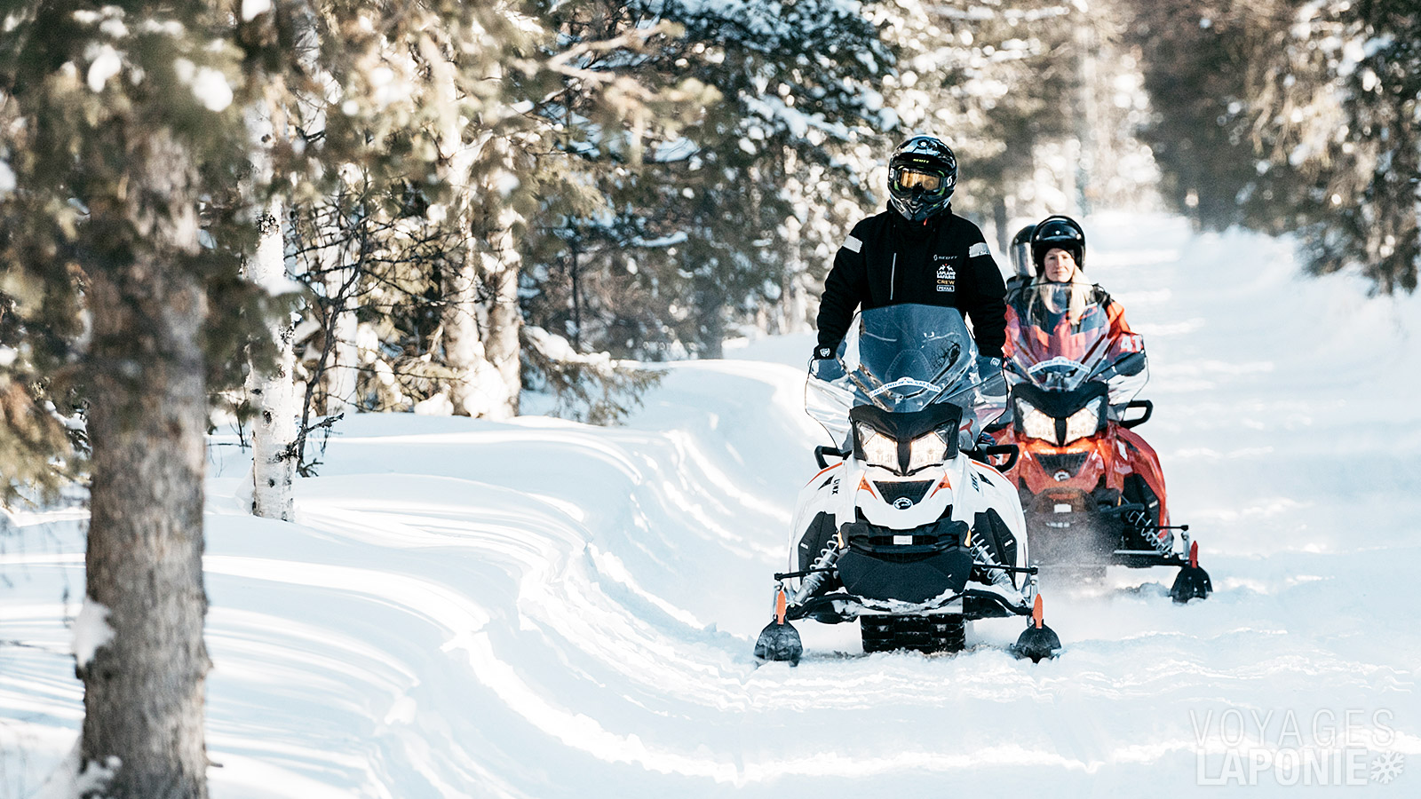 En motoneige à travers les forêts enneigées et le long des lacs gelés